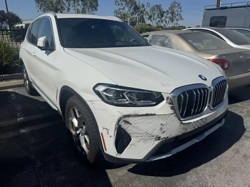 2022 BMW X3 with scrapes and paint transfer across the right side of the front bumper, before repair